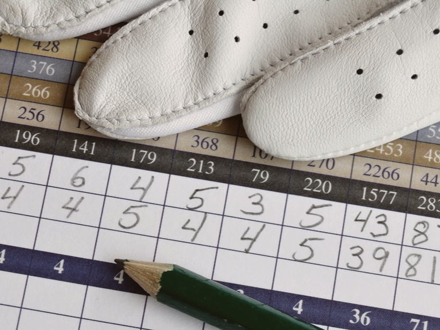 The old way — a paper golf scorecard, pencil, and glove